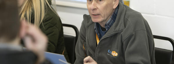 A person wearing an Eastlight fleece is talking to someone opposite him.