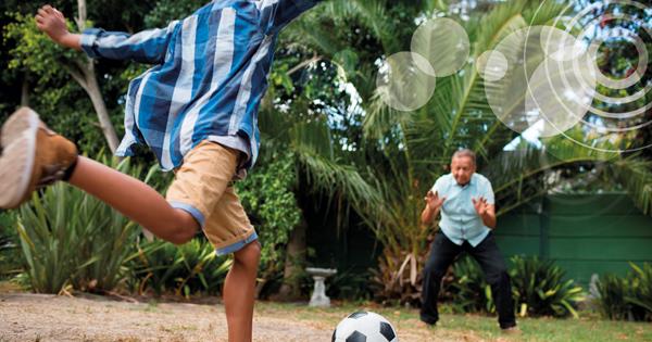 A young boy plays football with an older man