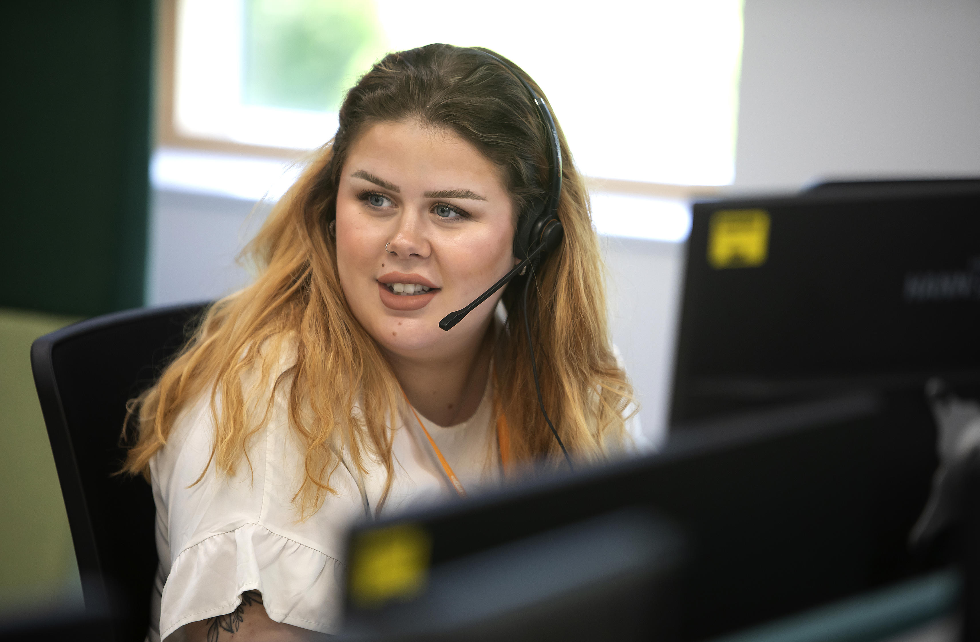 An Eastlight staff member wearing a headset and sitting at an office desk
