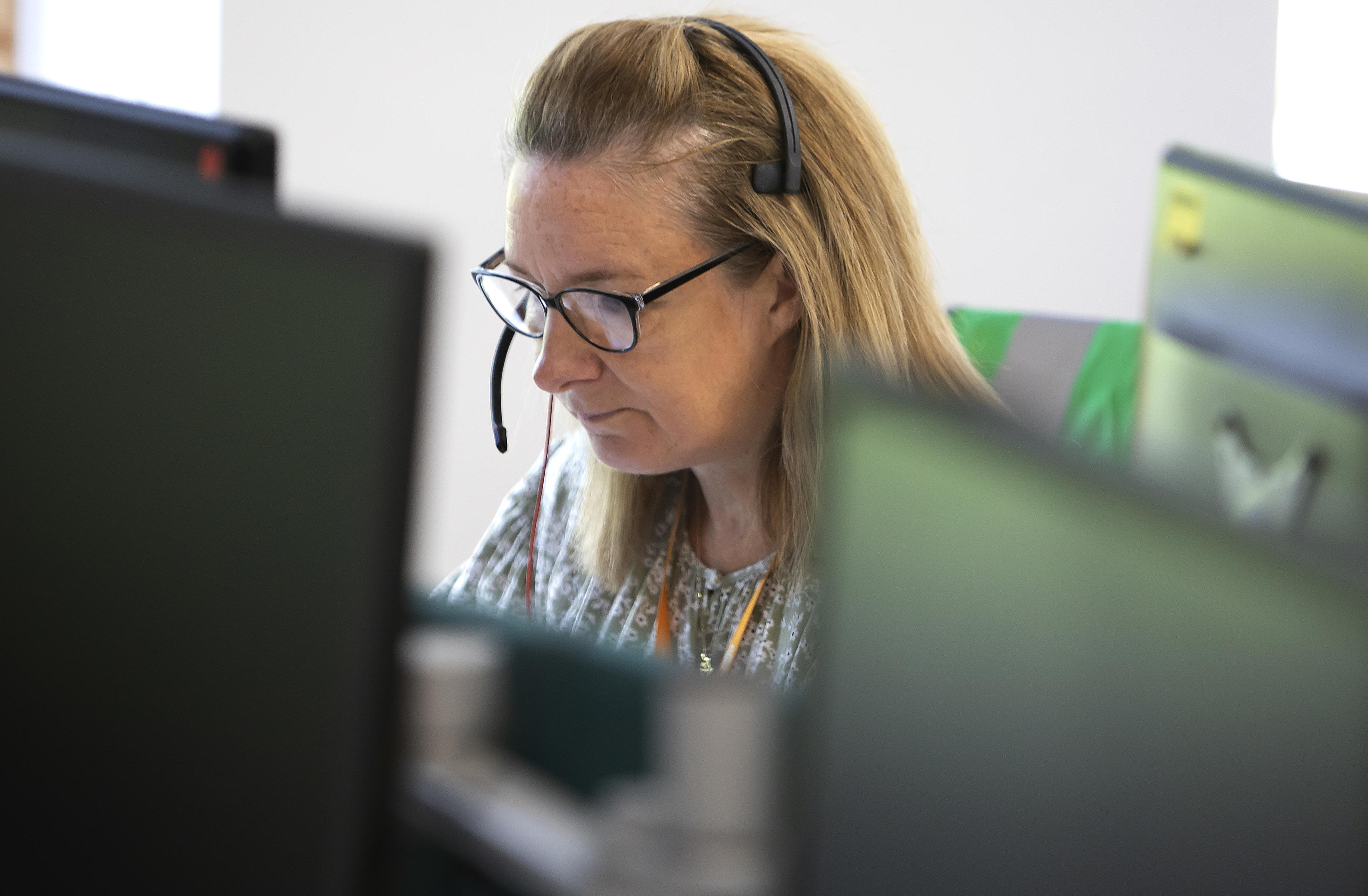 A person is wearing a headset and looking at a computer screen.