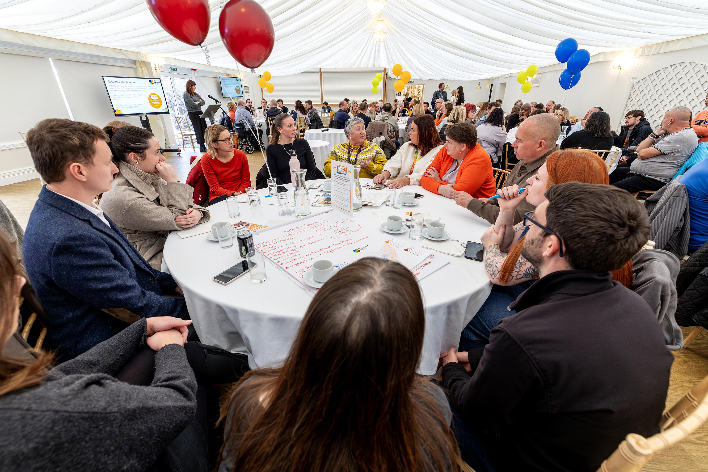 A group of Eastlight staff and residents sat around a table at a conference event.