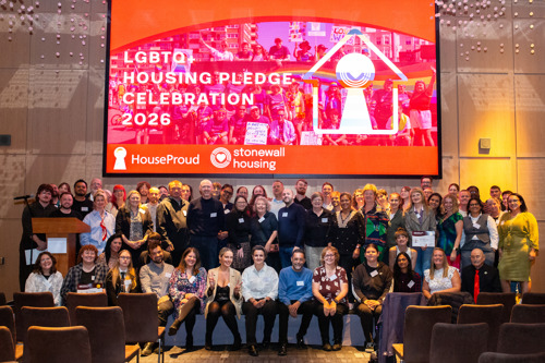 Group photo of attendees at the LGBTQ+ Housing Pledge Celebration 2026, in front of a large HouseProud and Stonewall Housing event screen.