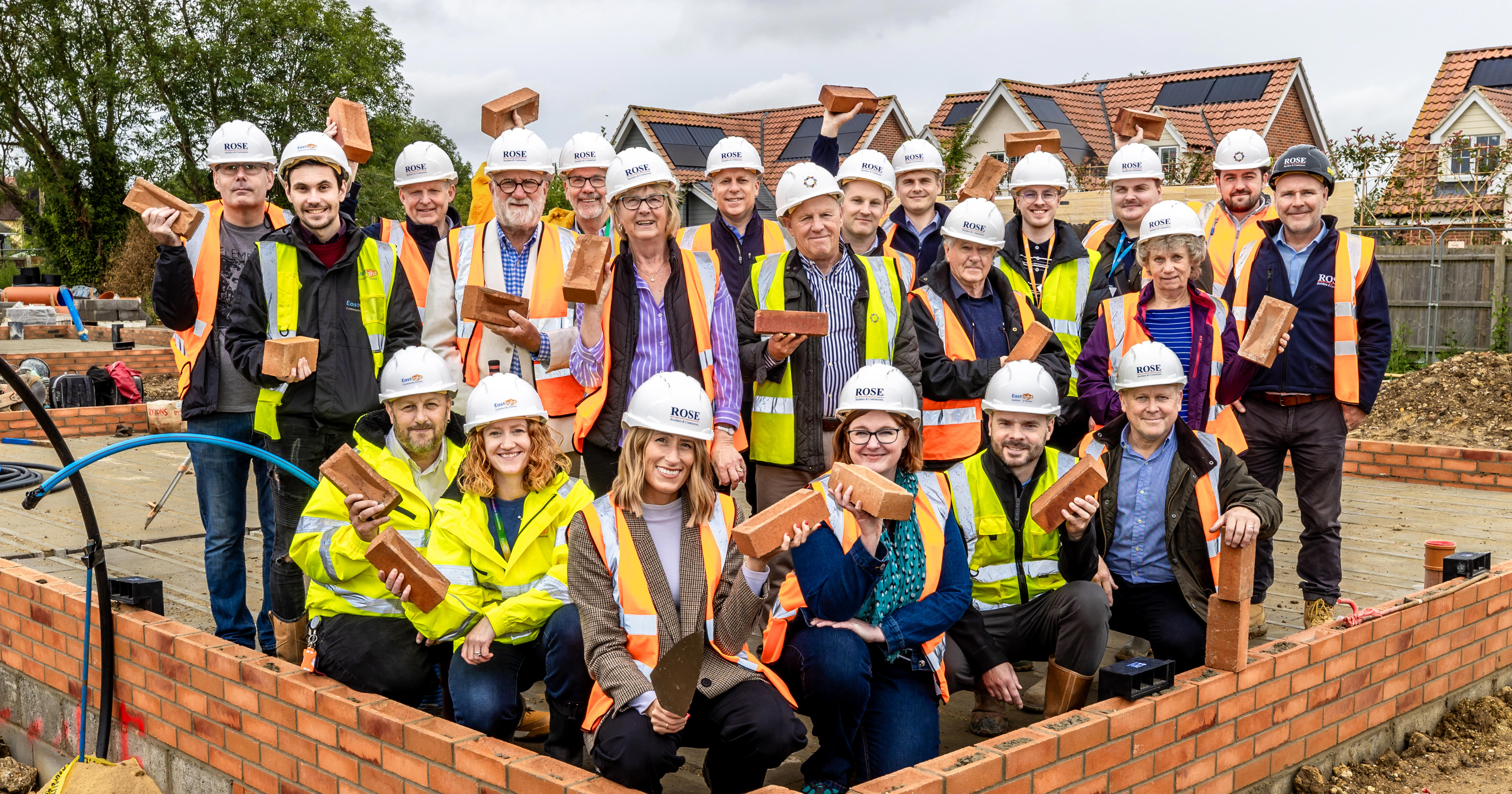 Lots of people wearing high vis standing on a building site and smiling