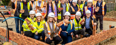 Lots of people wearing high vis standing on a building site and smiling
