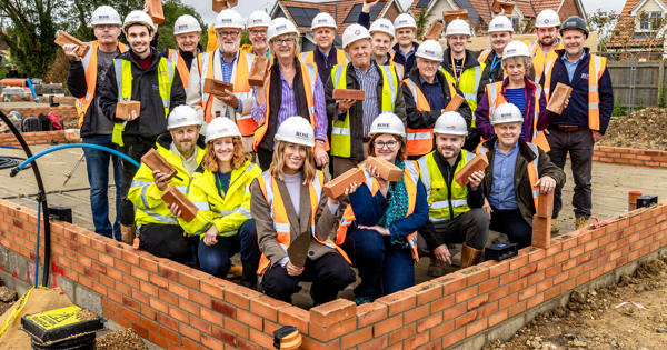 Lots of people wearing high vis standing on a building site and smiling