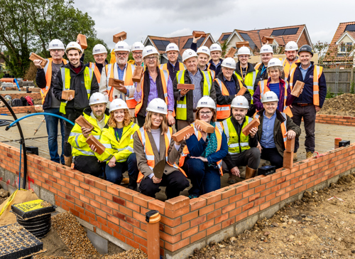 Lots of people wearing high vis standing on a building site and smiling
