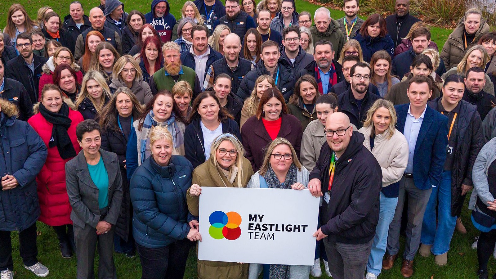 A large group of Eastlight staff members smiling and holding up a sign saying 'My Eastlight Team'