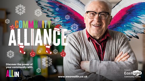 An older man smiling at the camera, with wings seemingly coming out from behind him. The background contains the words 'Community Alliance', surrounded by festive artwork (include christmas tree decorations and snowflakes)