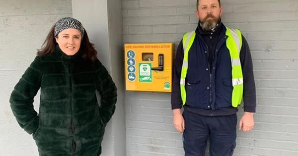 Two people standing next to a defibrillator