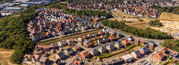 An aerial view of a large Eastlight new-build development, with completed homes, construction work in progress and surrounding neighbourhoods visible.