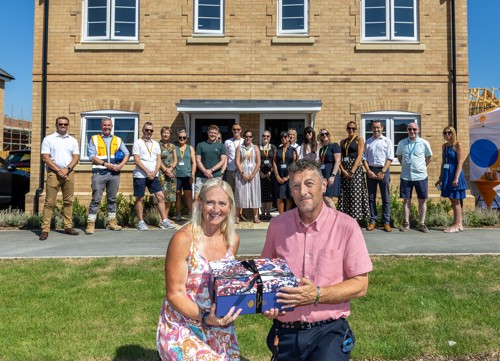 A resident, Eastlight staff and partners standing in front of new homes in Rivenhall