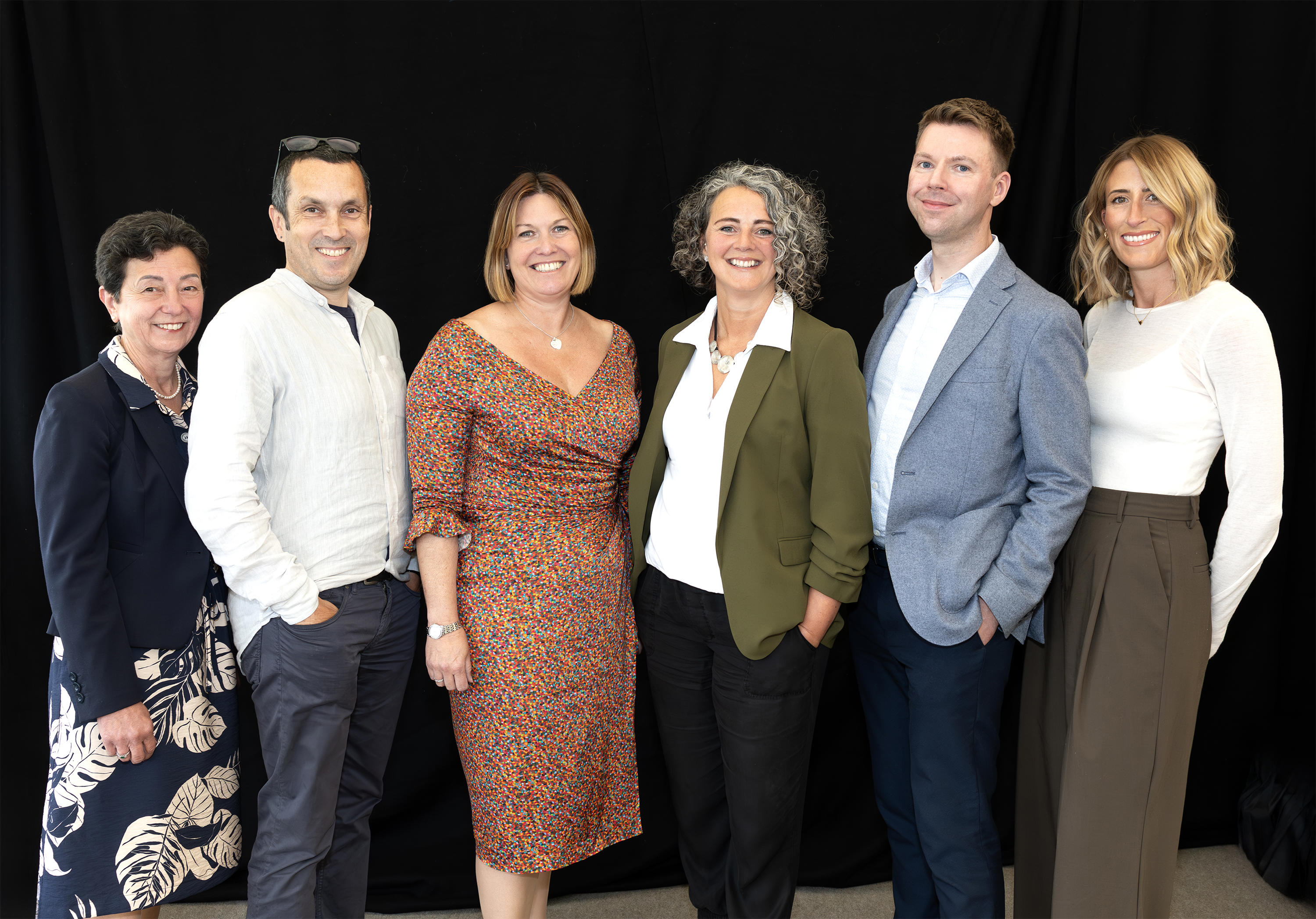 Eastlight's Leadership Team, stood in a group together, smiling at the camera. From left to right are: Sharon Ault (Chief People Officer); Dan Jones (Chief Information Officer); Emma Palmer (Chief Executive); Jo Barrett (Chief Strategy, Governance & Assurance Officer); David Mullen (Chief Finance Officer); and Charlotte Todd (Chief Property Officer). There is a black backdrop behind them. 