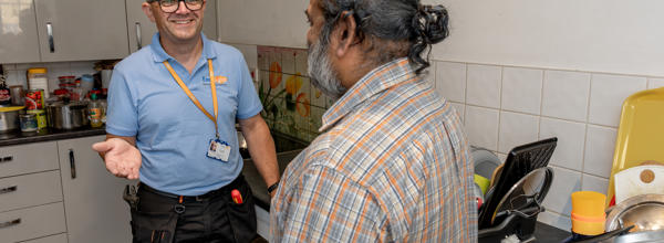 A member of Eastlight’s Home Solutions Team speaks with a resident in the resident’s kitchen during a home visit.