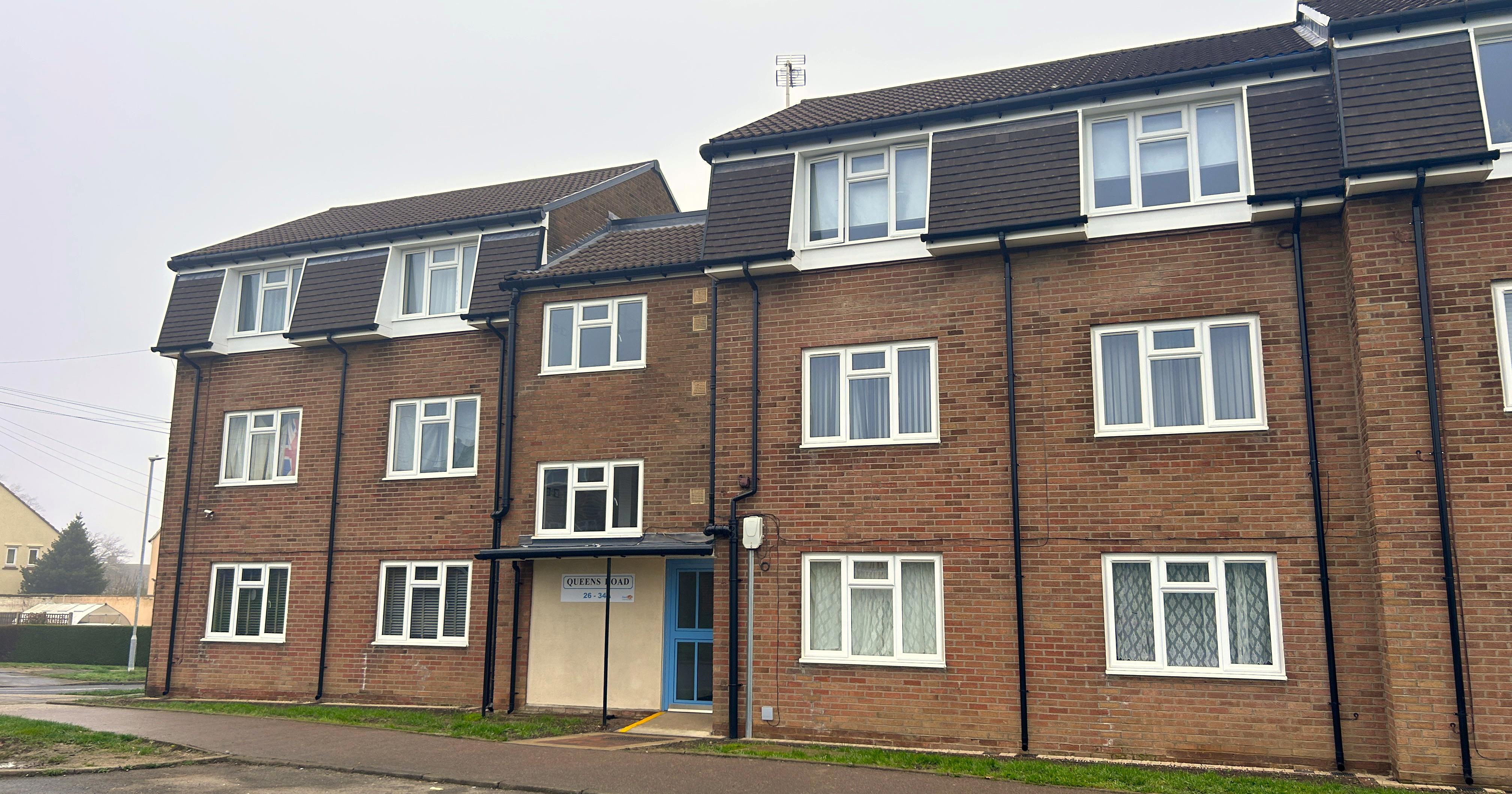 A block of three storey flats next to a road.