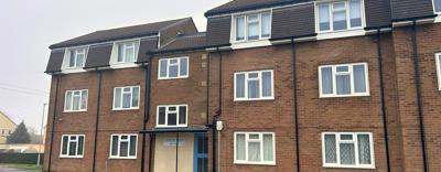 A block of three storey flats next to a road.