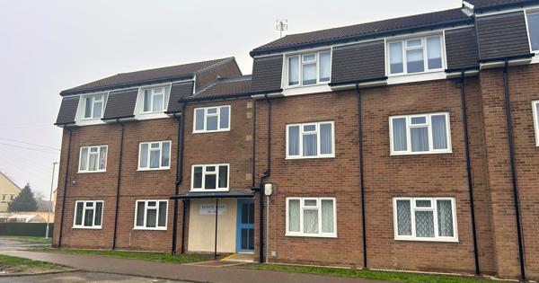 A block of three storey flats next to a road.