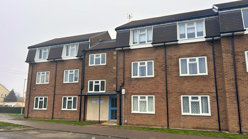 A block of three storey flats next to a road.