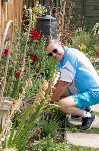 Jeff Spencer crouching by a flowerbed, smiling