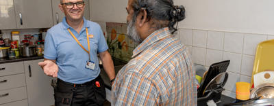 Two men are stood together. One is wearing an Eastlight blue polo shirt and the other is a resident. They are talking to each other.