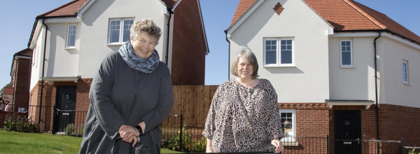 Hattie Llewellyn-Davies and Alison Inman stand next to each other and behind a road sign which reads Inman Avenue.