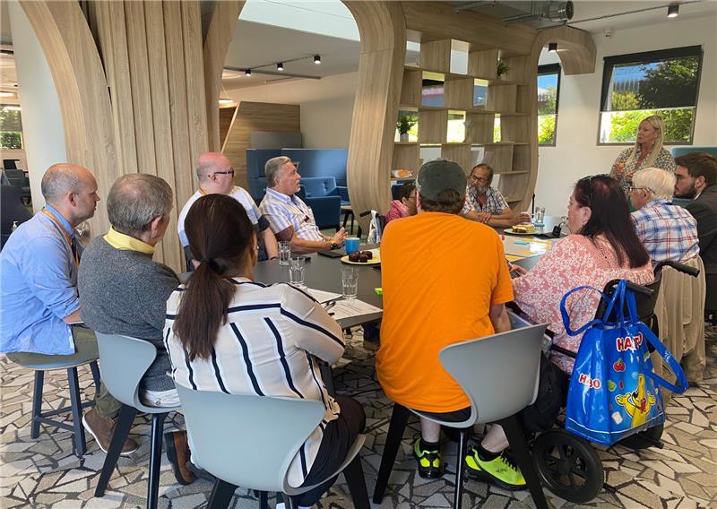 A group of residents are sat around a table at a meeting about shareholding.
