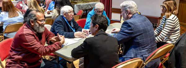 A group of residents and Eastlight colleagues are sat around a table. They are all talking.