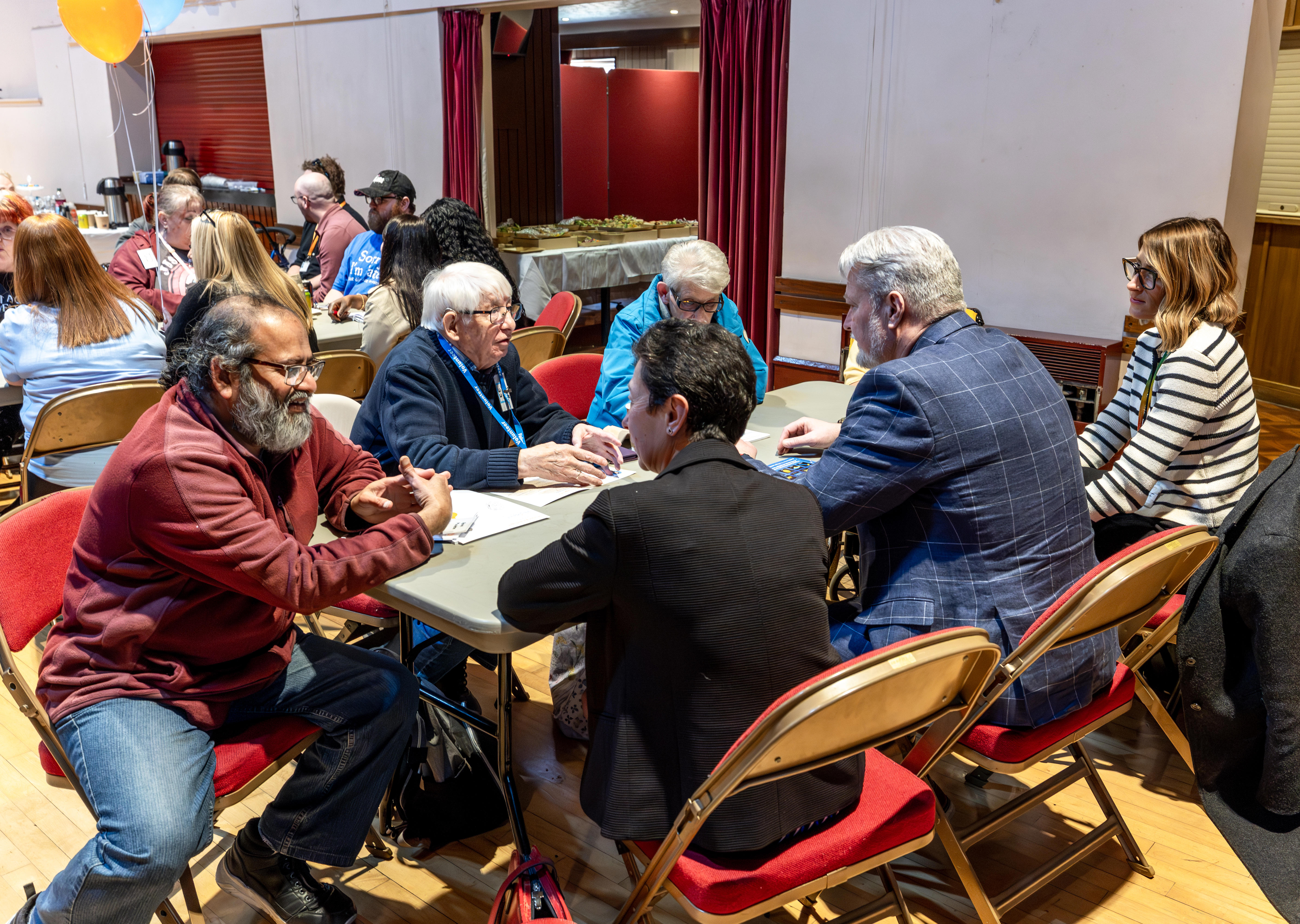 A group of residents and Eastlight colleagues are sat around a table. They are all talking.