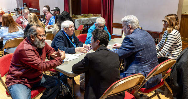 A group of residents and Eastlight colleagues are sat around a table. They are all talking.