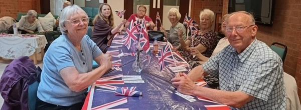 People smiling and sitting round a table with a Union Jack tablecloth