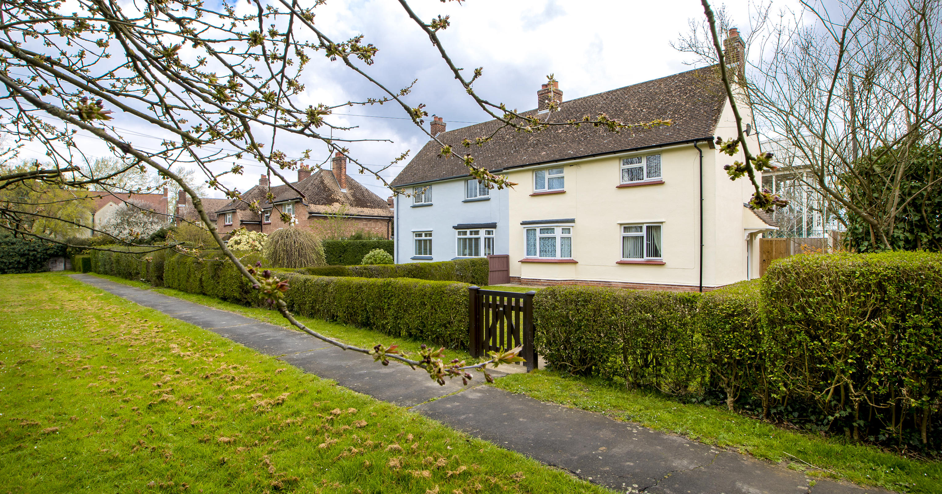 Two houses with a hedges around them and entrance gates.