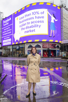Emma Palmer stood in Piccadilly Circus in front of a huge billboard for Purple Tuesday.