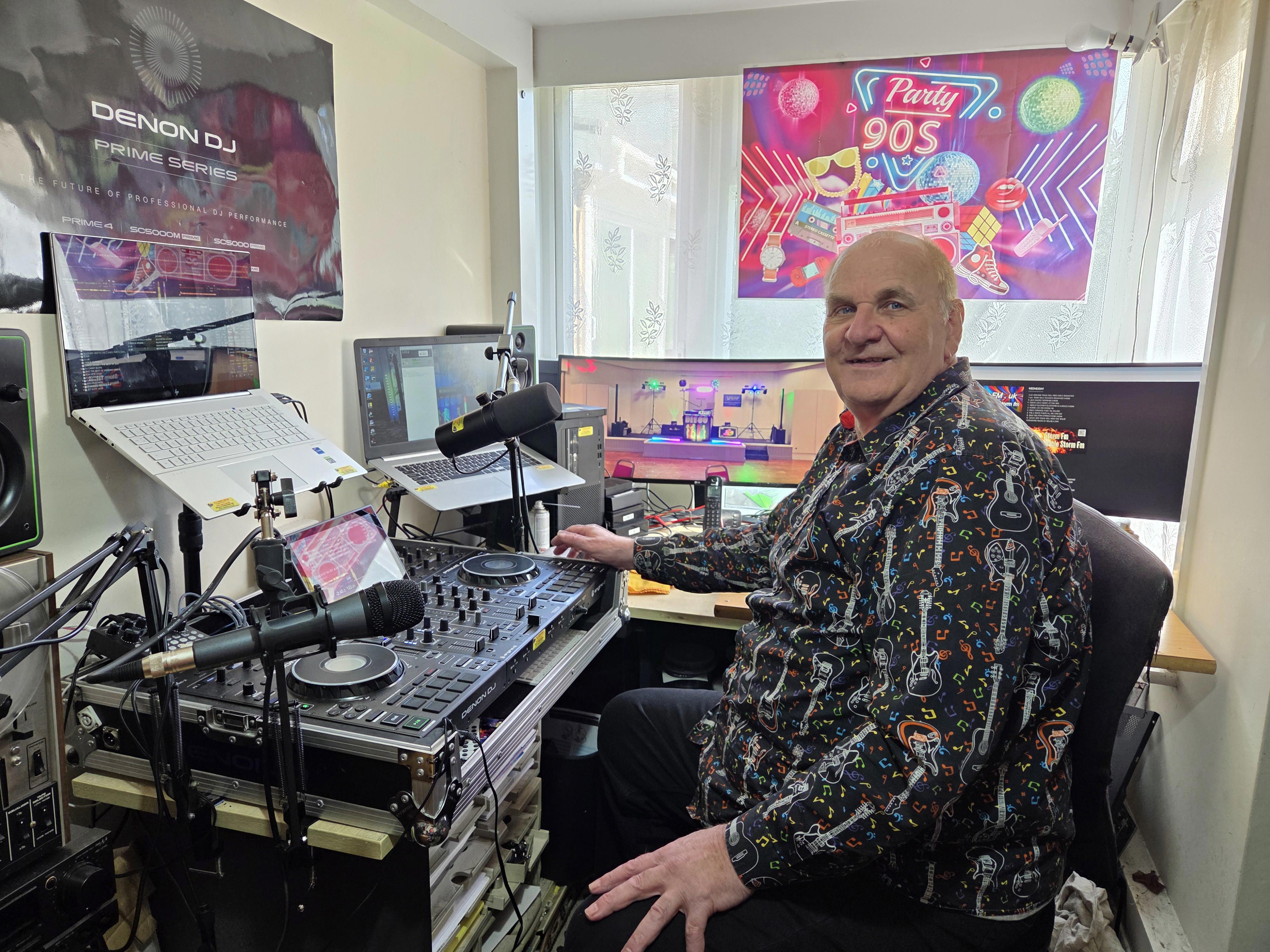 Dave Leslie is sat in front of his DJ Decks that he uses for his radio show on Storm FM.