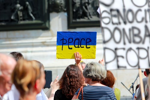 A woman holds a placard with the word peace written on and a Ukraine flag