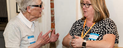 Two women are facing each other and talking.