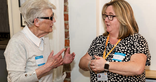 Two women are facing each other and talking.