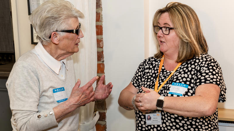 Two women are facing each other and talking.