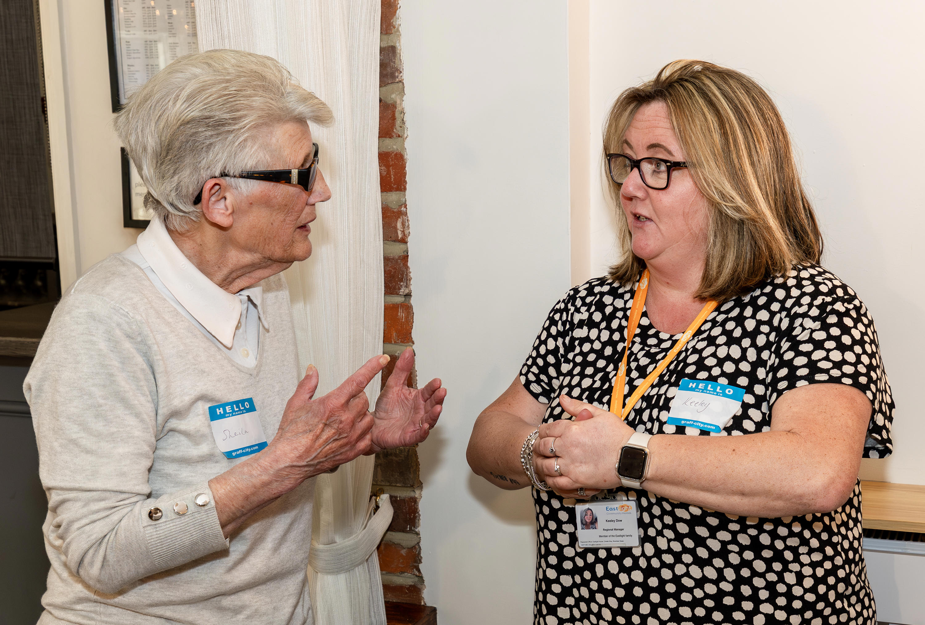 Two women are facing each other and talking.