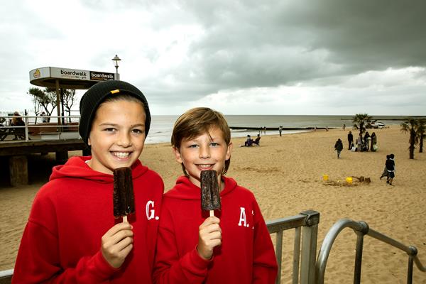 Two boys eating ice lollies at the beach