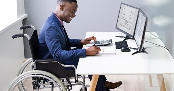 Man in a wheelchair doing paperwork at an office desk