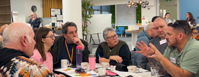 A group of Eastlight residents are sat around a table talking to an Eastlight repairs manager.