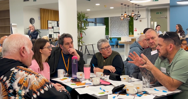 A group of Eastlight residents are sat around a table talking to an Eastlight repairs manager.