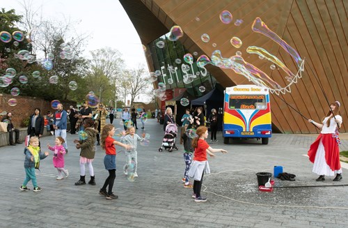 A group of children and a street entertainer playing with bubbles at Eastlight's All In community festival event