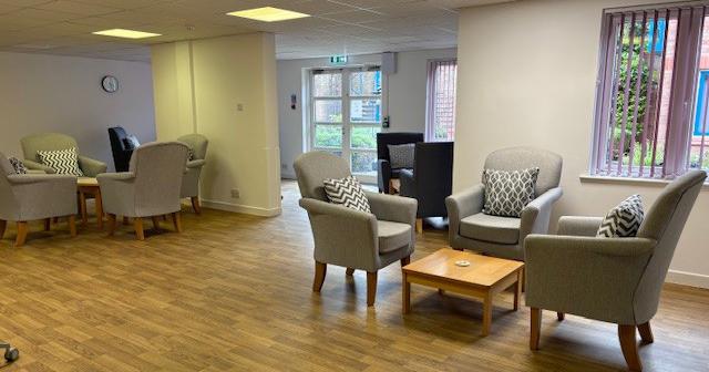 A wooden floored room with two groups of three single arms chairs sat around a small coffee table.