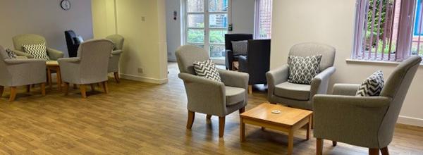 A wooden floored room with two groups of three single arms chairs sat around a small coffee table.