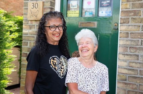 Two residents smiling outside their front door