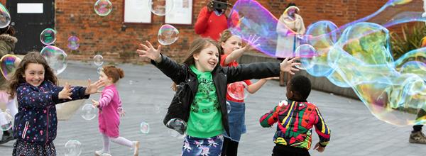 Children playing outside with large bubbles.