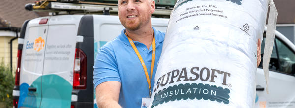 2.	A member of Eastlight Home Solutions  Team carrying a roll of loft insulation outside a resident's home as part of work to improve home warmth and energy efficiency.