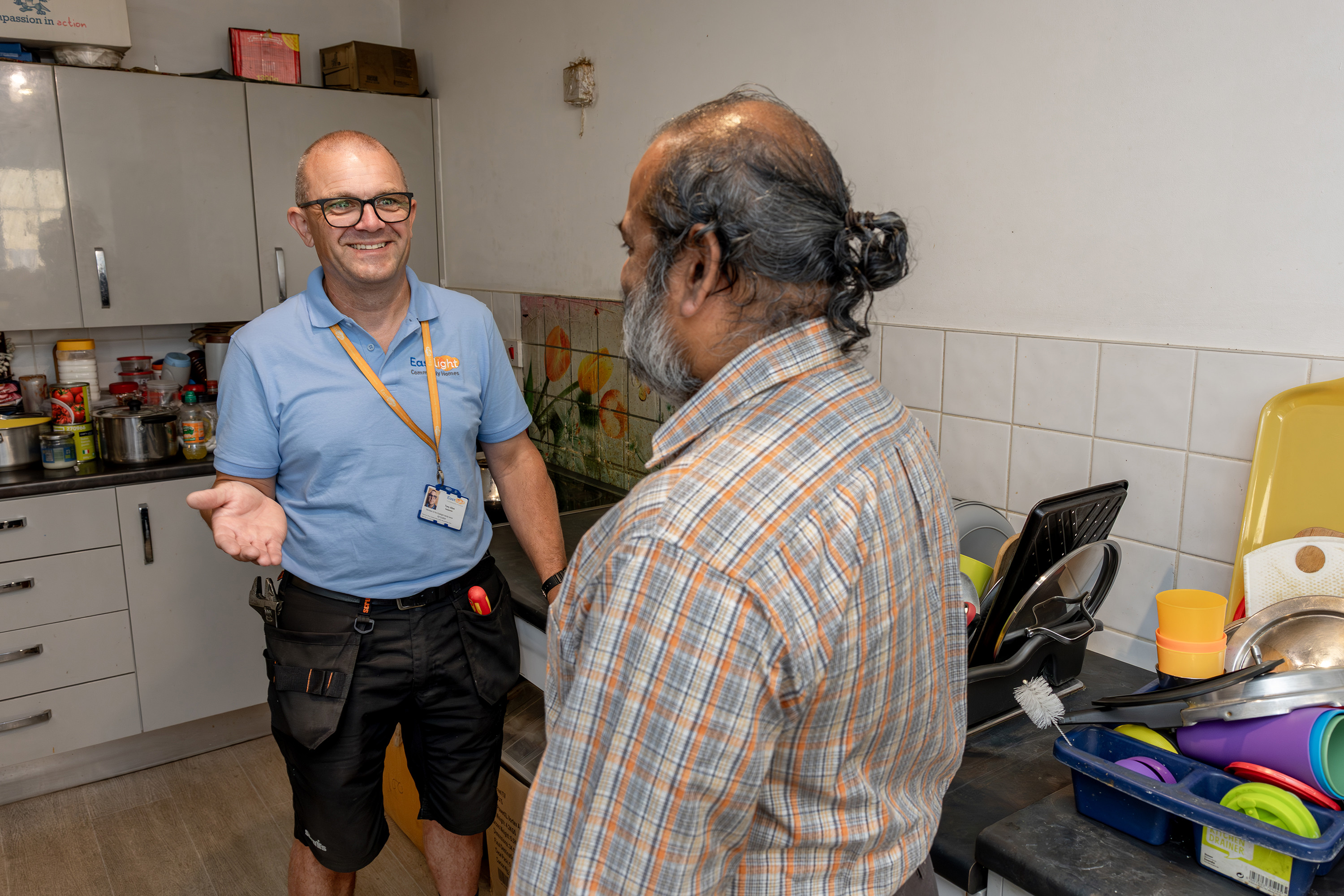 A member of Eastlight’s Home Solutions Team speaks with a resident in the resident’s kitchen during a home visit.